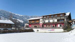 Een meerlaags gebouw met balkons, omgeven door besneeuwde bergen.