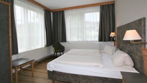 Een hotelkamer met een groot bed, een stoel, een bureau en twee bedlampen.