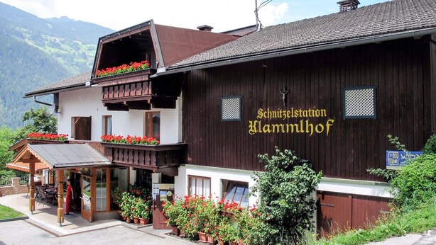 En traditionell byggnad i trä med en balkong och blomlådor, med skylten "Schnitzelstation Klammlhof".