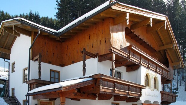 A two-story wooden building with a balcony, a dining area, and a staircase leading to the entrance. - Nice apartment for 4 guests with WIFI, TV and balcony (Mitterdorf)
