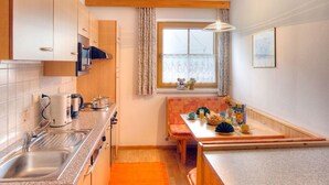 A compact kitchen with a sink, stove, and dining area. - Nice apartment for 4 guests with WIFI, TV and balcony (Mitterdorf)