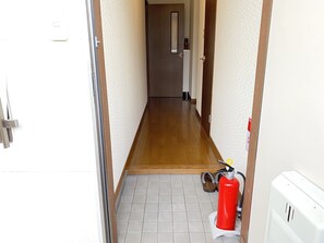 A narrow hallway with wooden flooring, a fire extinguisher, and a white wall. - KASUMI-an 4 (Kumamoto)