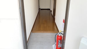 Kapea käytävä, jossa on puulattia ja laattapintainen osuus päässä. Palosammutin on kiinnitetty seinään.