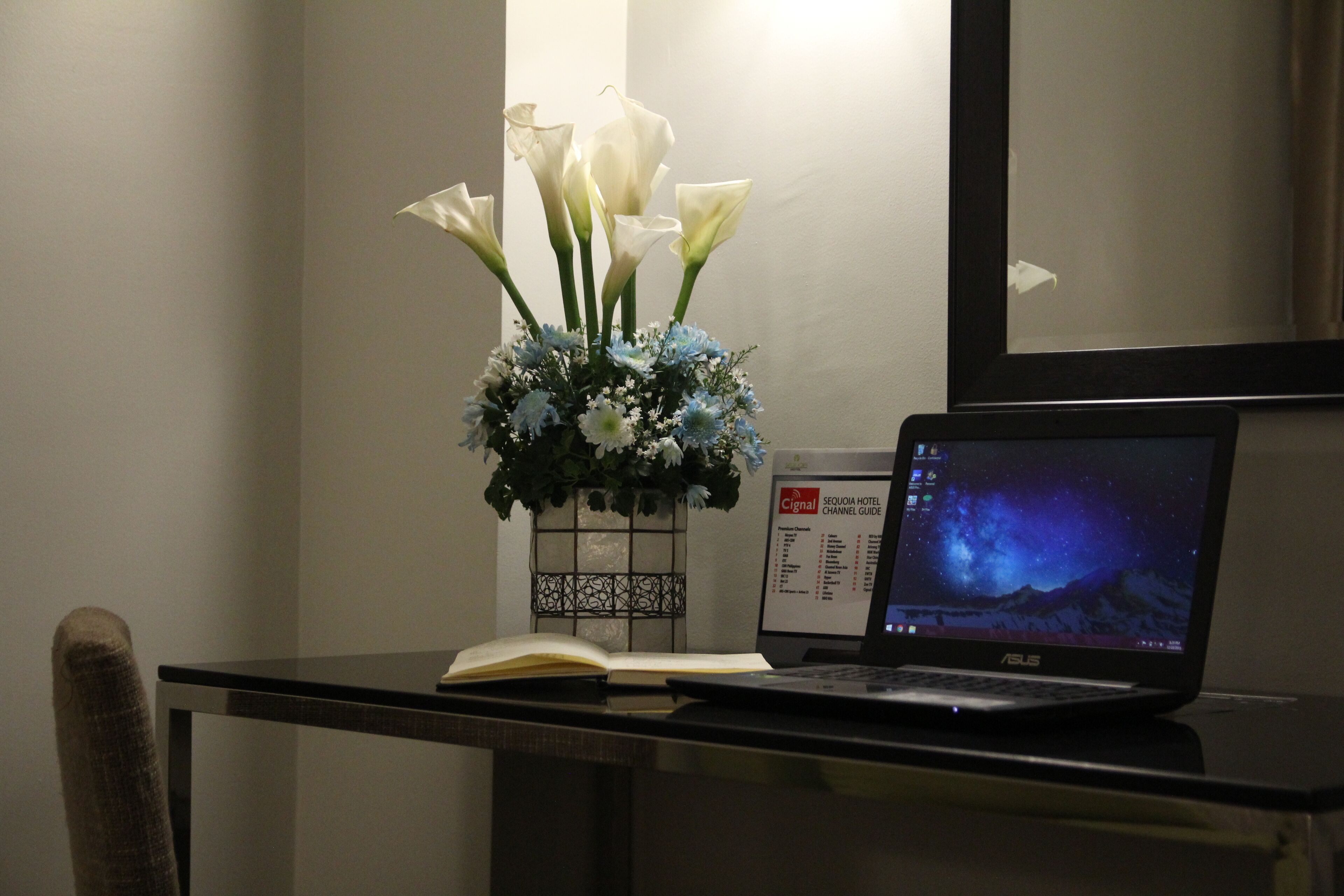 Una computadora portátil sobre un escritorio, con un florero y un libro.