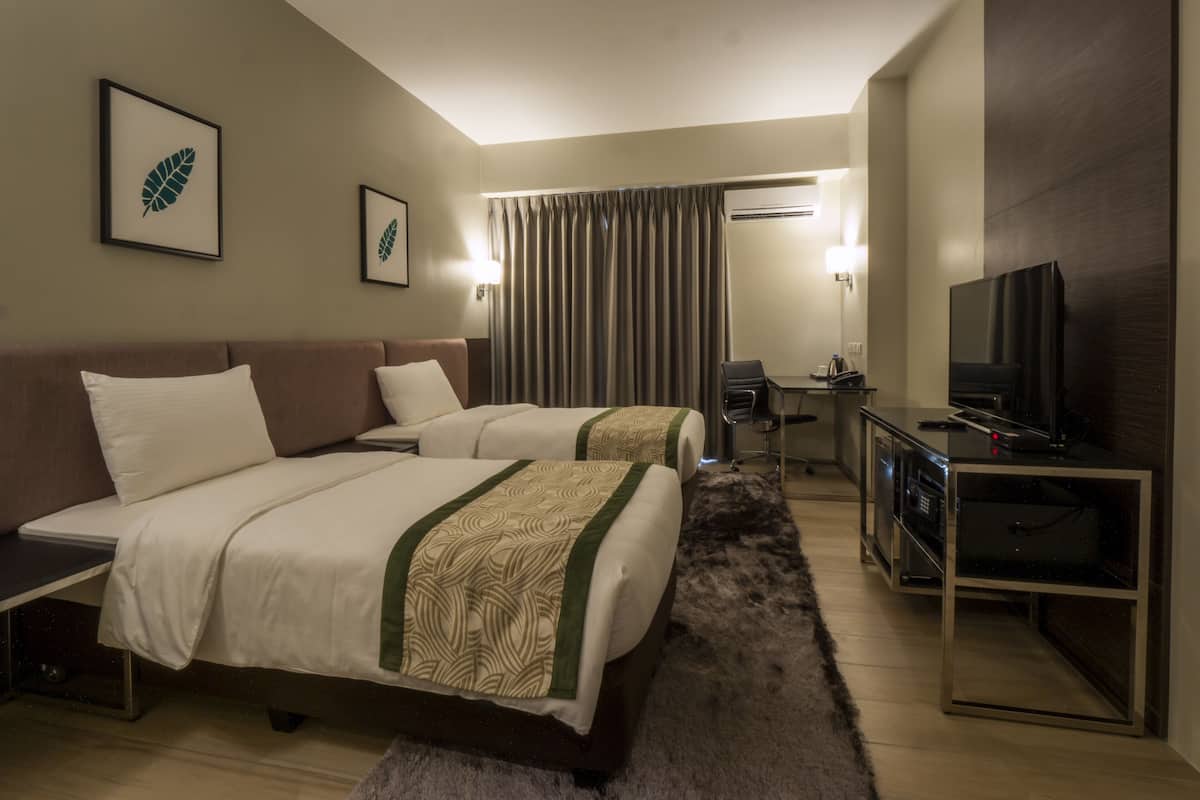 A hotel room with two beds, a desk with a chair, a television, and a mirror.