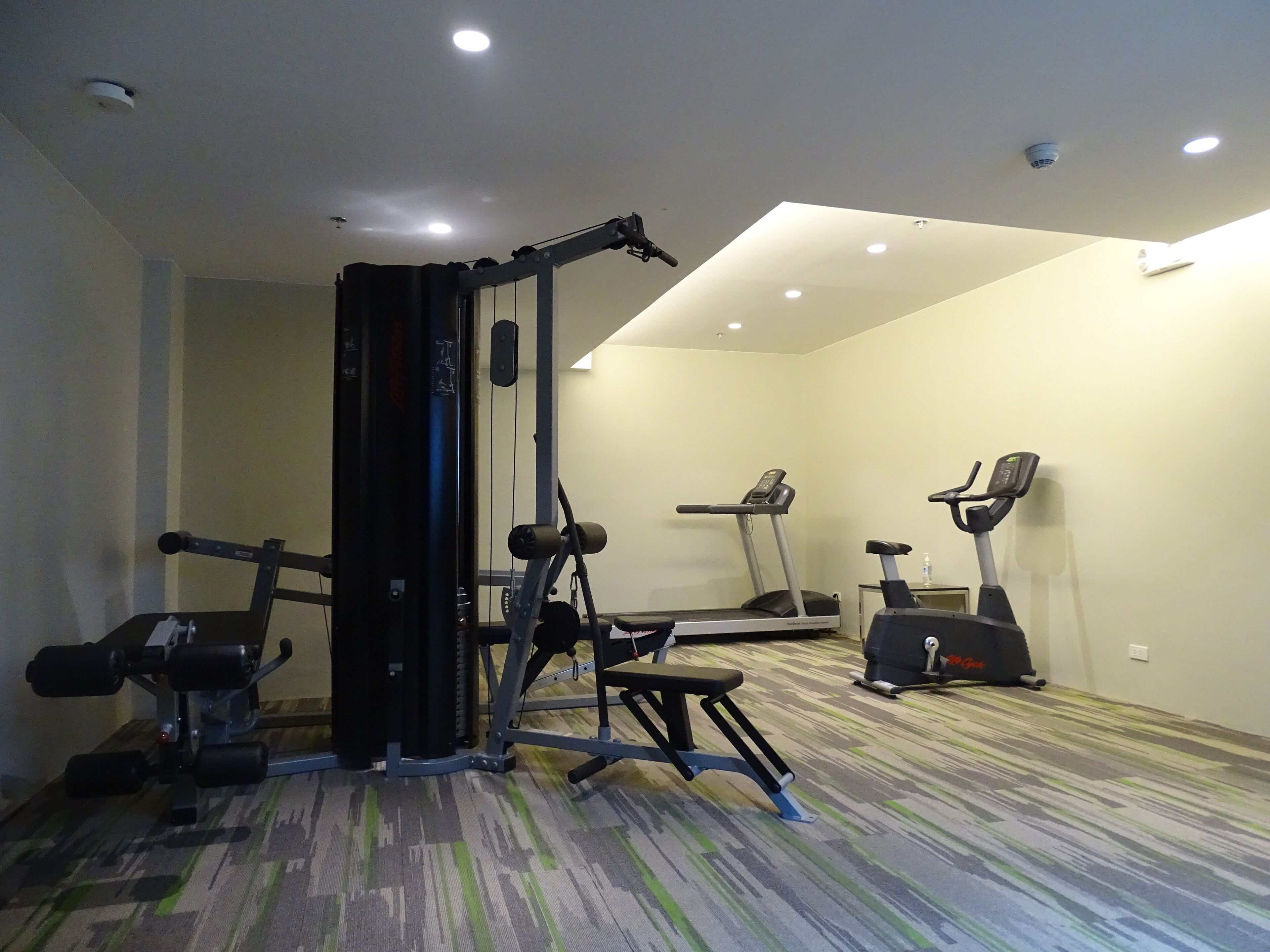 A gym with exercise equipment including a bench press, a squat rack, and treadmills.
