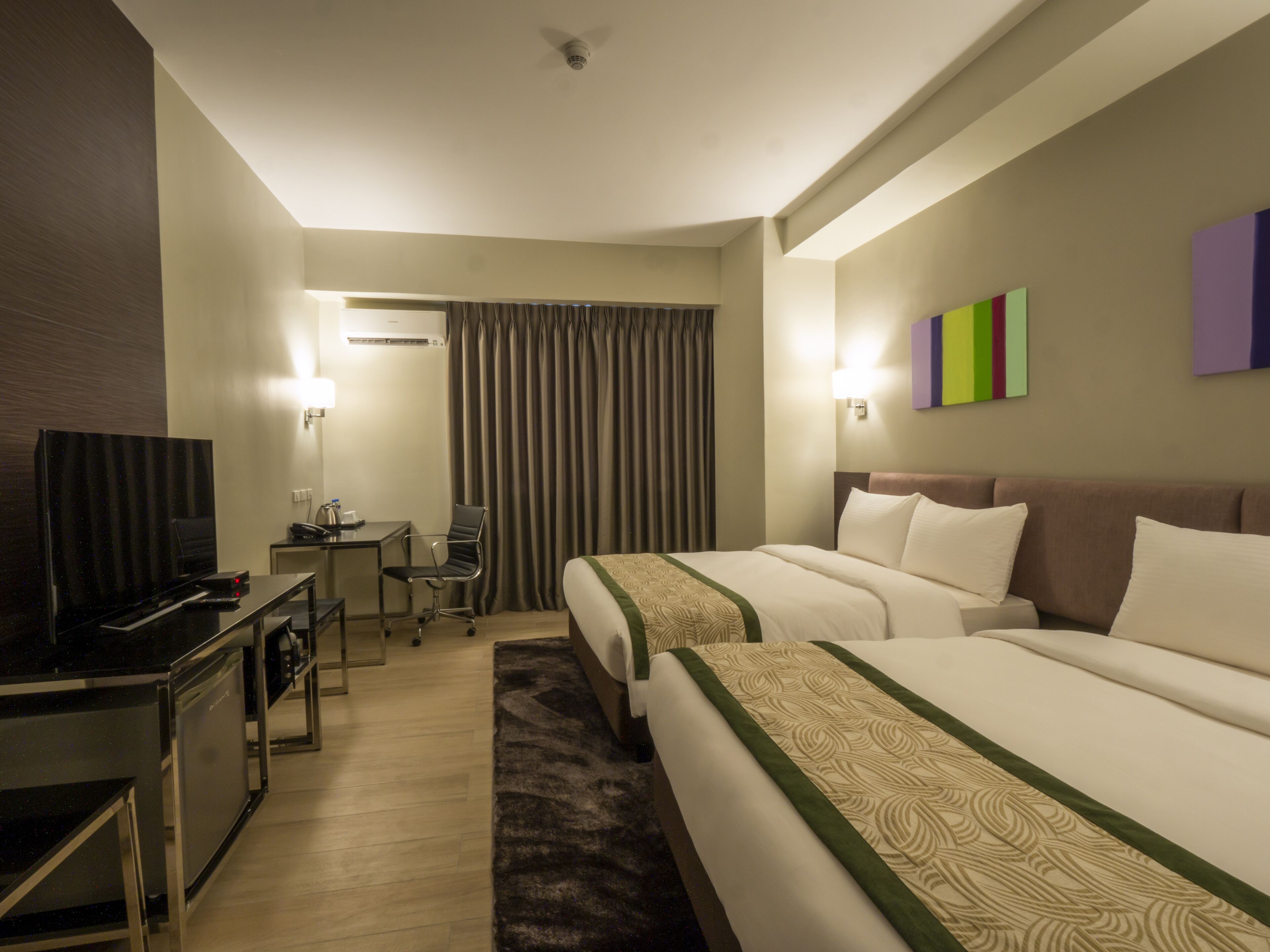 A hotel room with two beds, a desk, a television, and a chair.