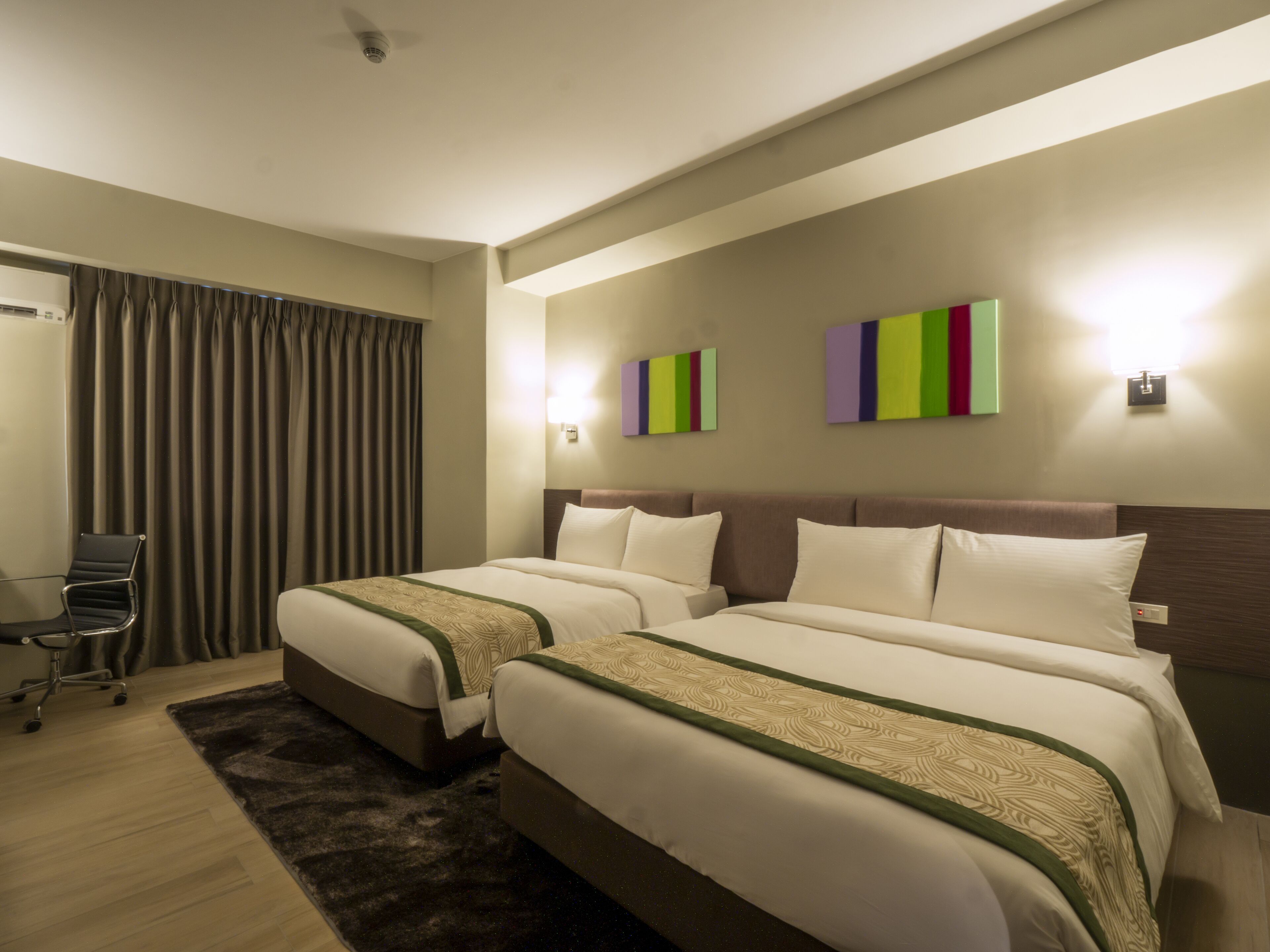 A hotel room with two beds, a desk, and a chair.