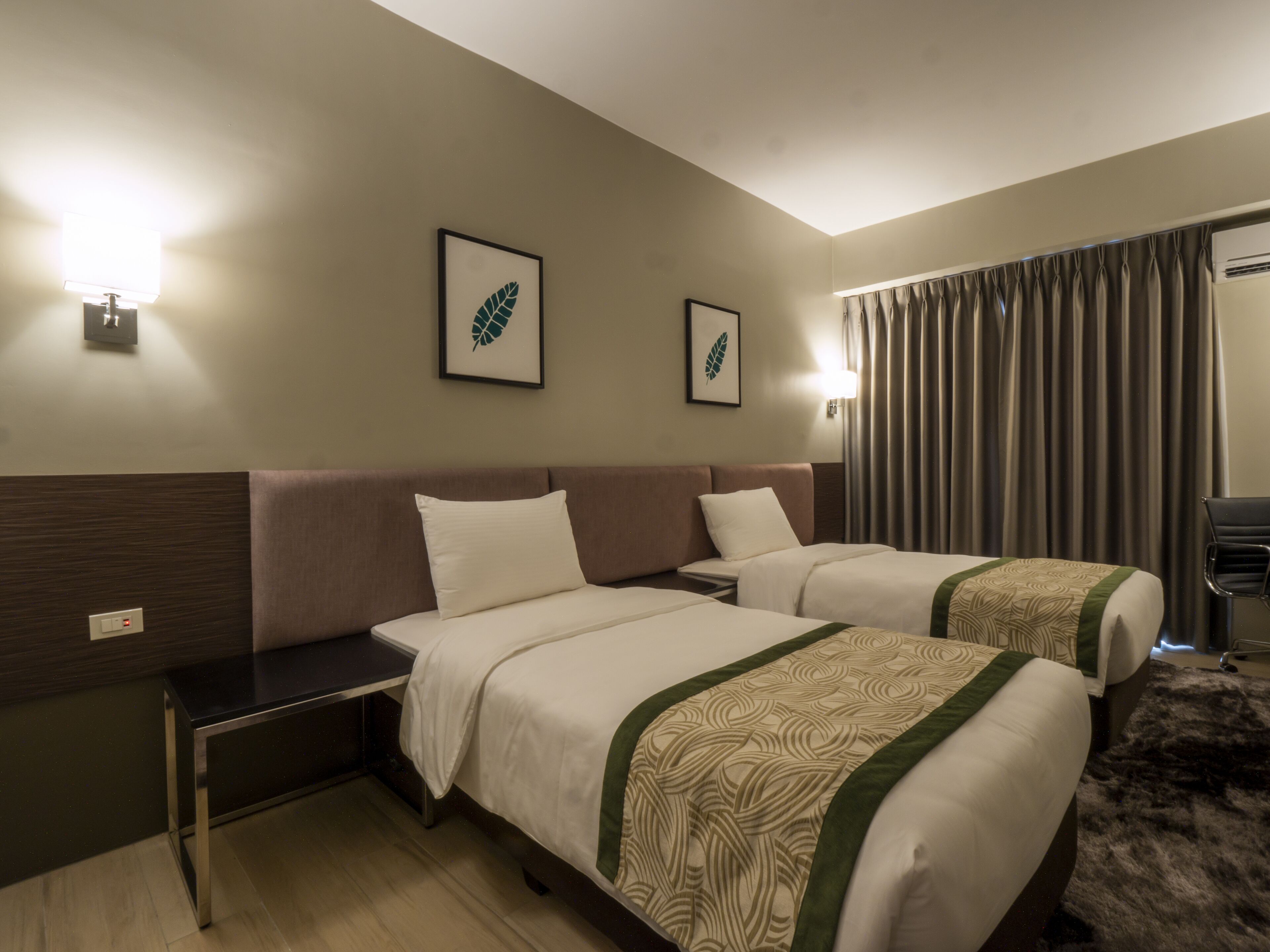 A hotel room with two beds, a desk, a chair, and a large window with curtains.