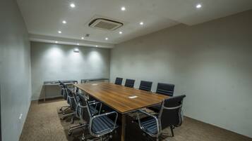 Uma sala de conferências com uma mesa comprida, seis cadeiras e piso coberto por carpete.