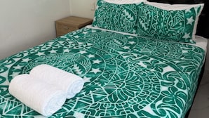 A bed with a patterned bedspread, a pillow, and a folded towel. - Moeroa Villa - In the heart of Town. (Avarua)