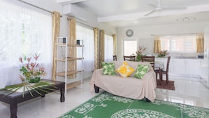 A modern living room with a sofa, dining table, and kitchen in the background. - Moeroa Villa - In the heart of Town. (Avarua)