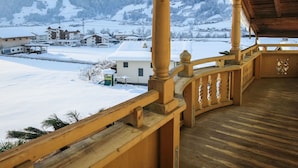 Un balcón de madera con vistas a un pueblo nevado y montañas.