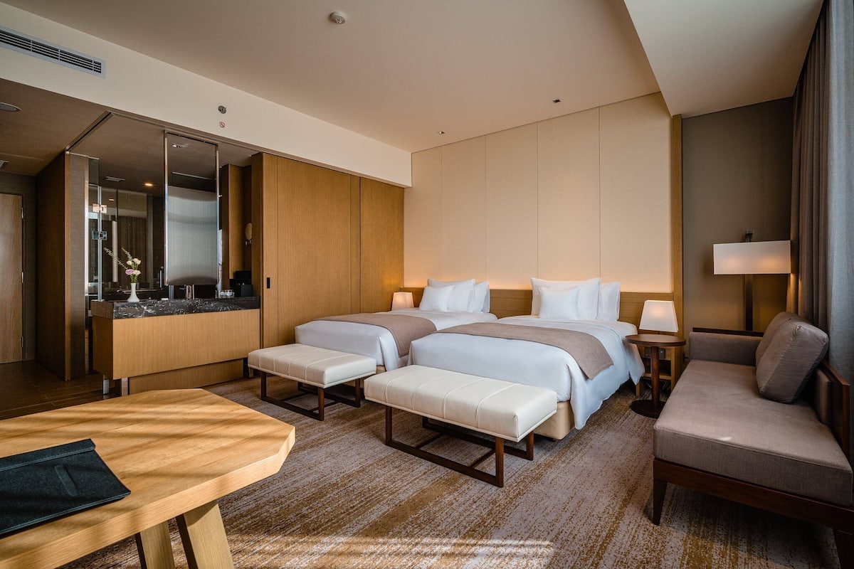 Ein Hotelzimmer mit einem großen Bett, einem Schreibtisch, einem Stuhl und einem kleinen Tisch.