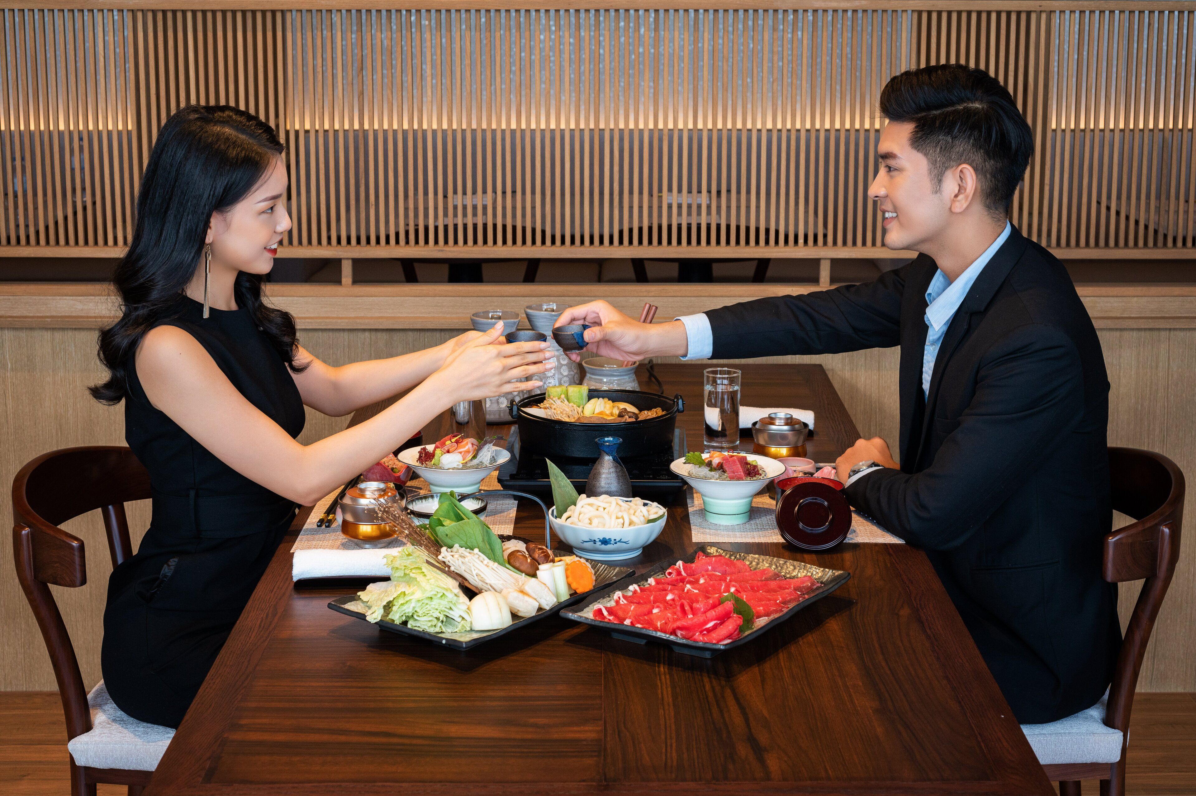 Una mesa de comedor con varios platos y una olla caliente.