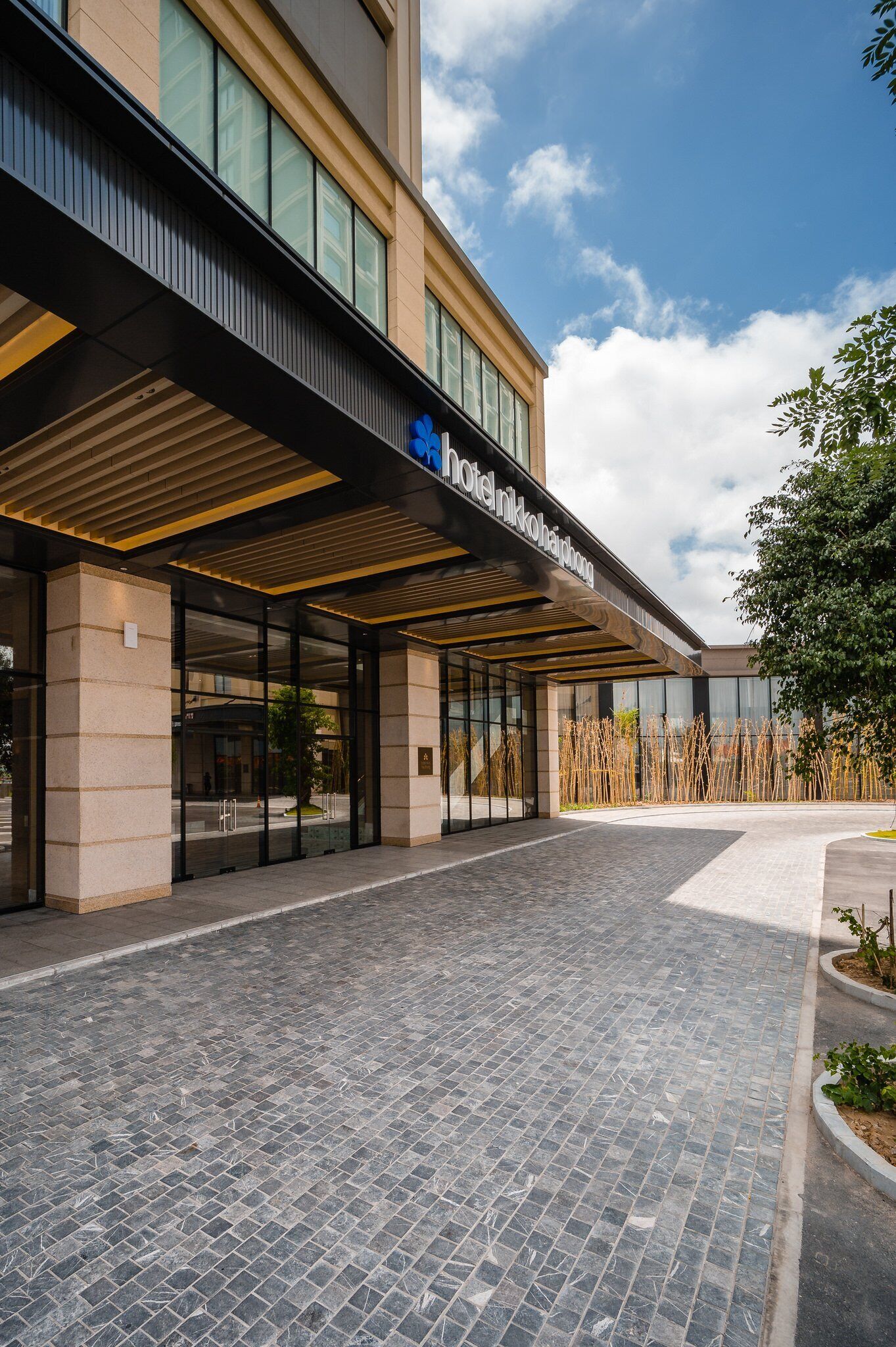 A hotel entrance with a modern design, featuring a covered walkway and a clear view of the building's facade.