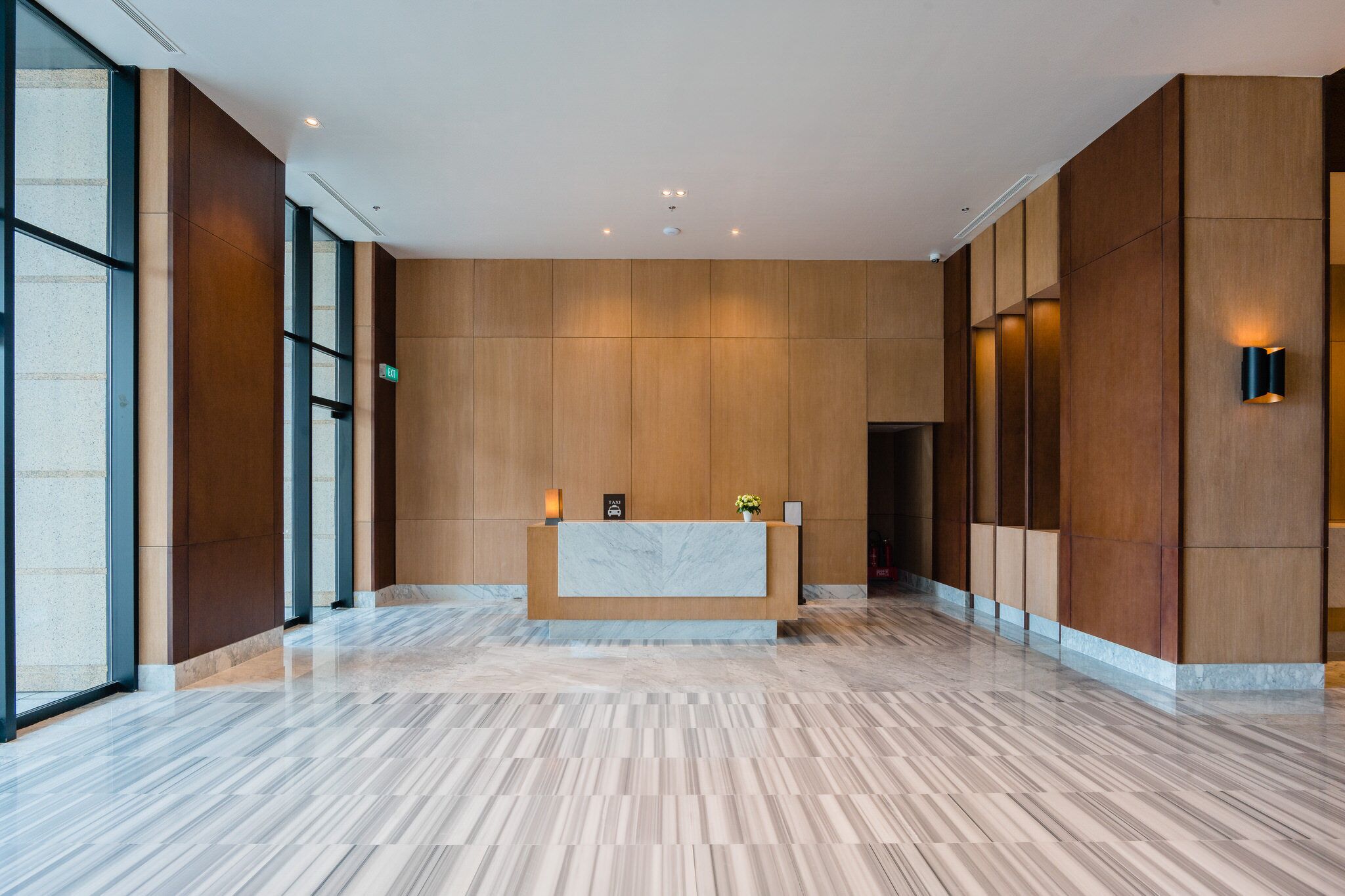 A reception area with a marble reception desk, wooden panel walls, and a polished marble floor.