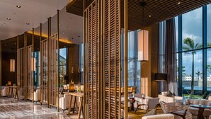 Un hall d’entrée spacieux au design moderne, doté d’un long comptoir de réception, de coins salons confortables et de grandes fenêtres offrant une vue sur l’extérieur.