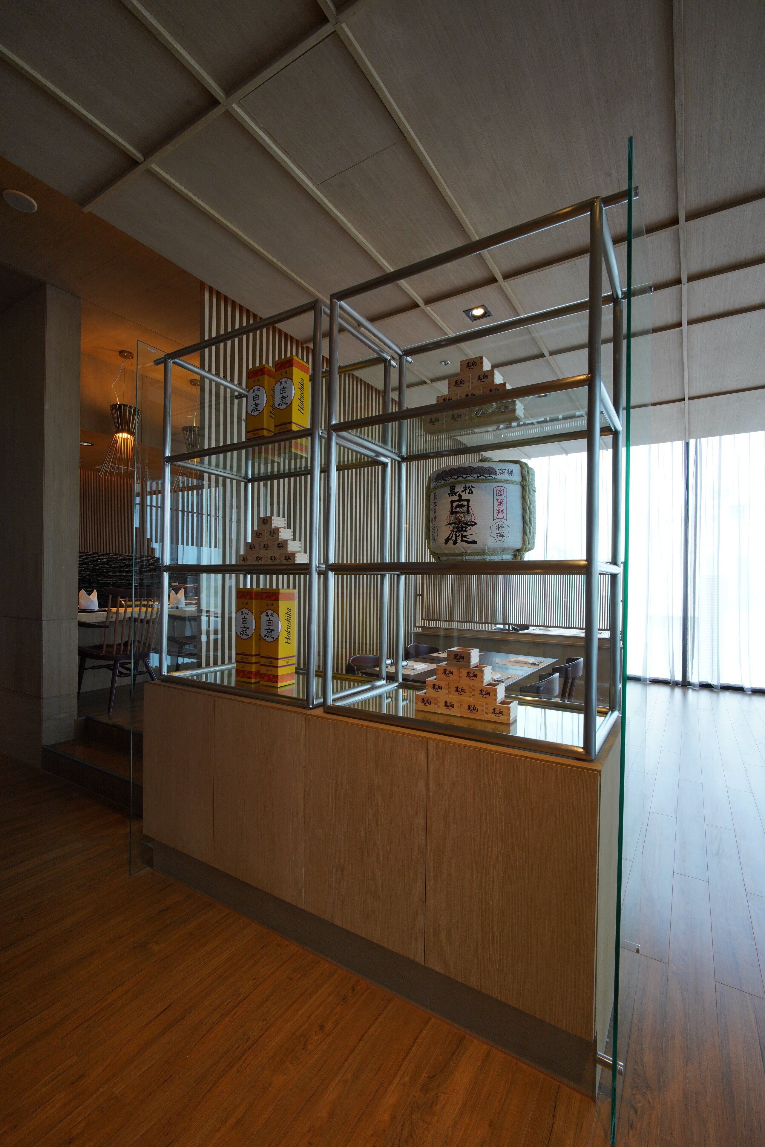 A modern interior with a wooden counter and metal shelving displaying various items.