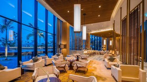 Eine großzügige Lobby mit moderner Möblierung, großen Fenstern und Blick nach außen.