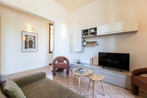 A modern living room with a sofa, armchairs, a TV, and a bookshelf. - Rosselli Palace apartment 2 (Florence)