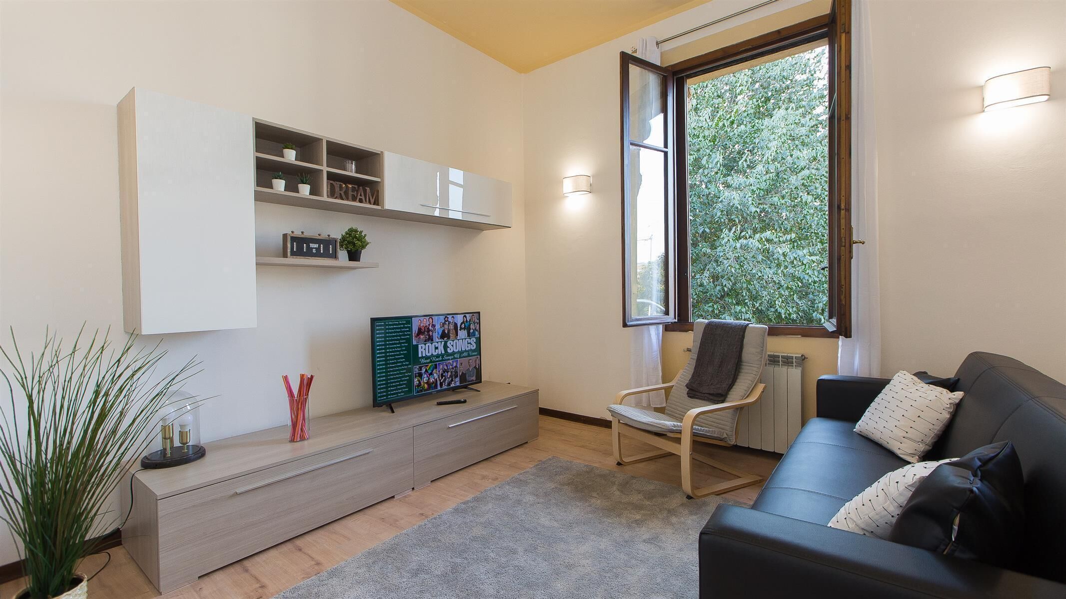 A modern living room with a TV, a bookshelf, a chair, and a sofa.