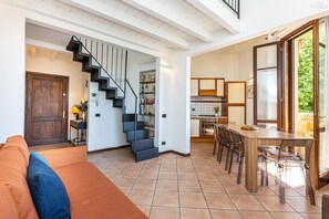 Un grand espace de vie comprenant un escalier, une table à manger avec des chaises et un coin cuisine.