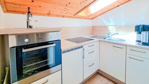 A compact kitchen with a built-in oven, a sink, and a window above the countertop. - Cosy apartment for 4 guests with WIFI, TV, terrace and panoramic view (Wildschönau)