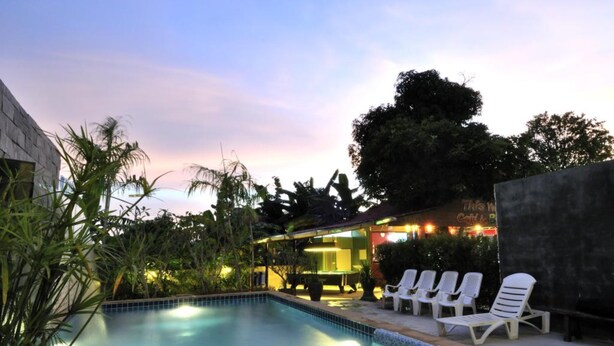 A swimming pool with lounge chairs and a bar area. - Serene Villa (Chalong)