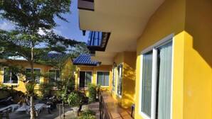 A yellow building with large windows and a covered walkway. - Serene Villa (Chalong)