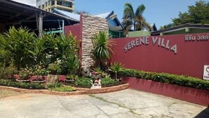 A building with a sign reading "SERENE VILLA" surrounded by greenery and a parking area. - Serene Villa (Chalong)