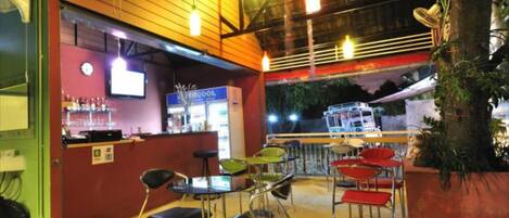 Un espace bar intérieur avec un comptoir, des tabourets de bar et des luminaires suspendus.