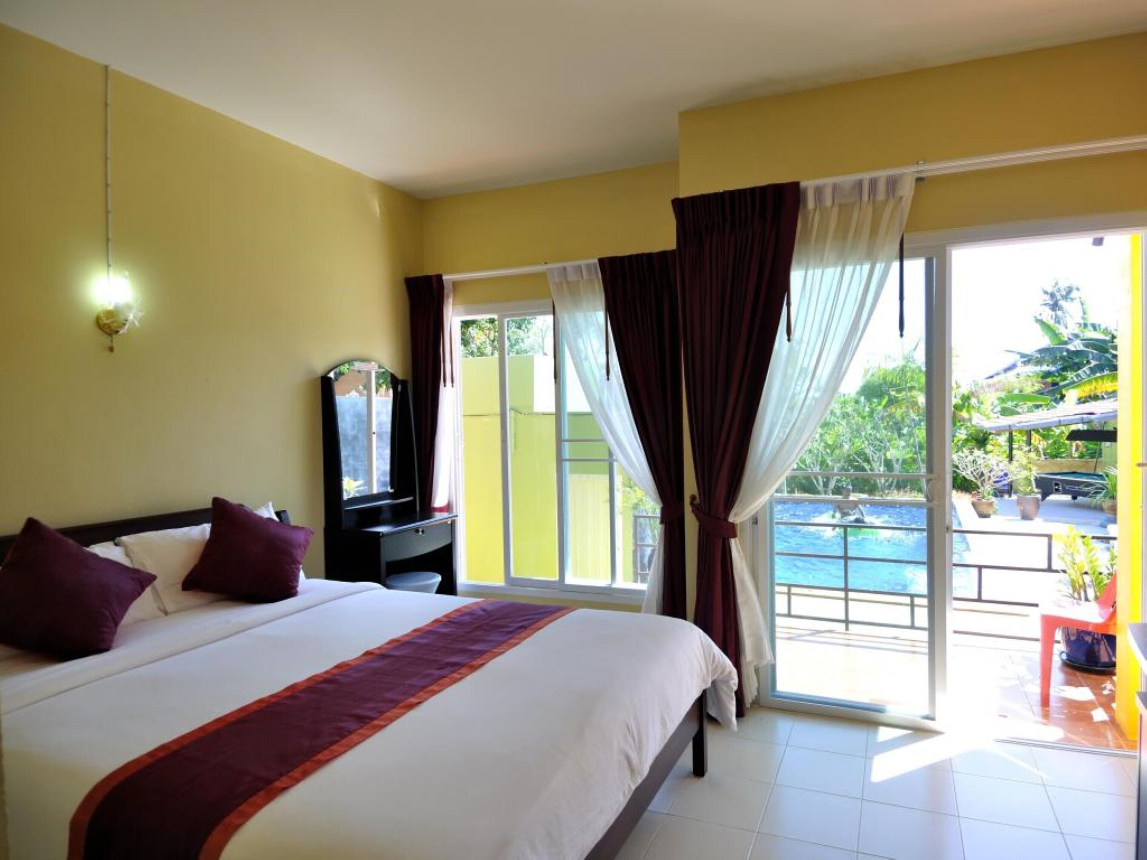 A hotel room with a large bed, a TV on a stand, a sliding glass door leading to a pool area.