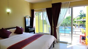 A hotel room with a large bed, a TV on a stand, a sliding glass door leading to a pool area. - Serene Villa (Chalong)