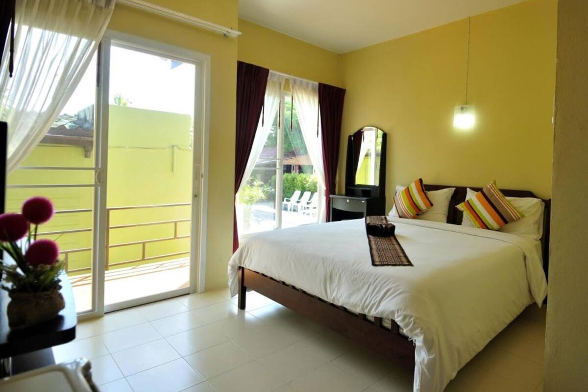 Habitación de hotel con cama, escritorio, silla, espejo y vistas al exterior a través de una puerta corredera.