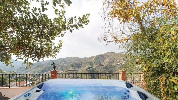 A hot tub with a mountain view, surrounded by greenery and a metal railing. - Villa La Posada, Canillas de Albaida (Canillas de Albaida)