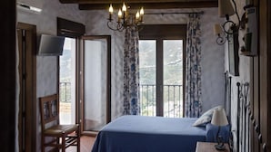 A bedroom with two beds, a chair, a TV, and a balcony with curtains. - Villa La Posada, Canillas de Albaida (Canillas de Albaida)