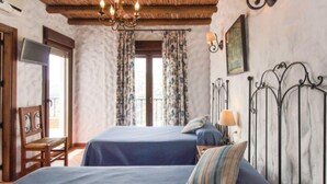 A bedroom with two beds, a chandelier, a TV, and a balcony door. - Villa La Posada, Canillas de Albaida (Canillas de Albaida)