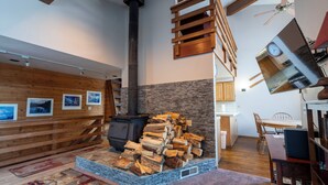 Una habitación acogedora con chimenea, paredes de madera, zona de comedor y pared espejada.