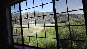 Una habitación con un ventanal que ofrece vistas a un lago, montañas y un área boscosa.