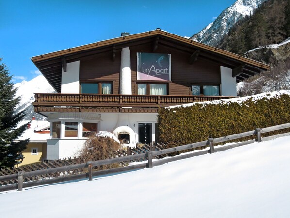 Un albergo di montagna a due piani con facciata in legno, un balcone e un cartello che riporta 'Inn Apart'.