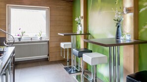 A modern kitchen with wooden paneling, a window with a view, a radiator, and bar stools. - Cosy apartment for 2 people with WIFI, TV and pets allowed (Solden)