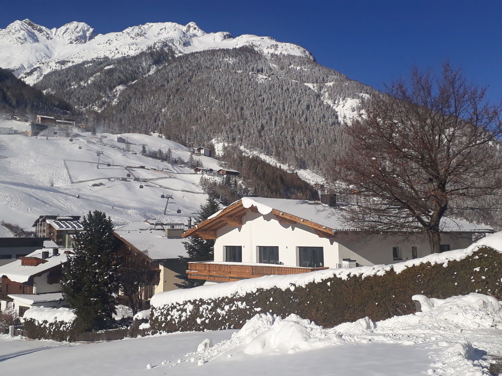 Un paysage de montagne enneigé, avec un chalet en bois et un télésiège en arrière-plan.