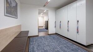 A hallway with a blue carpet, a bench, a wardrobe with lanyards, and a framed picture on the wall. - Cosy apartment for 2 people with WIFI, TV and pets allowed (Solden)