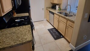 A compact kitchen with a stove, sink, and cabinets. - PRIVATE CONDO IN BEAUTIFUL GATED COMMUNITY IN SEVEN HILLS (Henderson)
