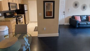 A modern kitchen with built-in appliances, a dining area with a glass table, and a living room with a dark floor and a black leather sofa. - PRIVATE CONDO IN BEAUTIFUL GATED COMMUNITY IN SEVEN HILLS (Henderson)