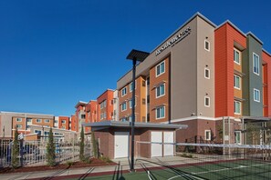 Een hotel met meerdere verdiepingen, met een modern design, met een combinatie van baksteen en beplating als buitenkant, en een helderblauwe lucht op de achtergrond.
