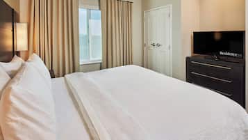 A hotel room with a large bed, a television, a wardrobe, and a window with curtains.
