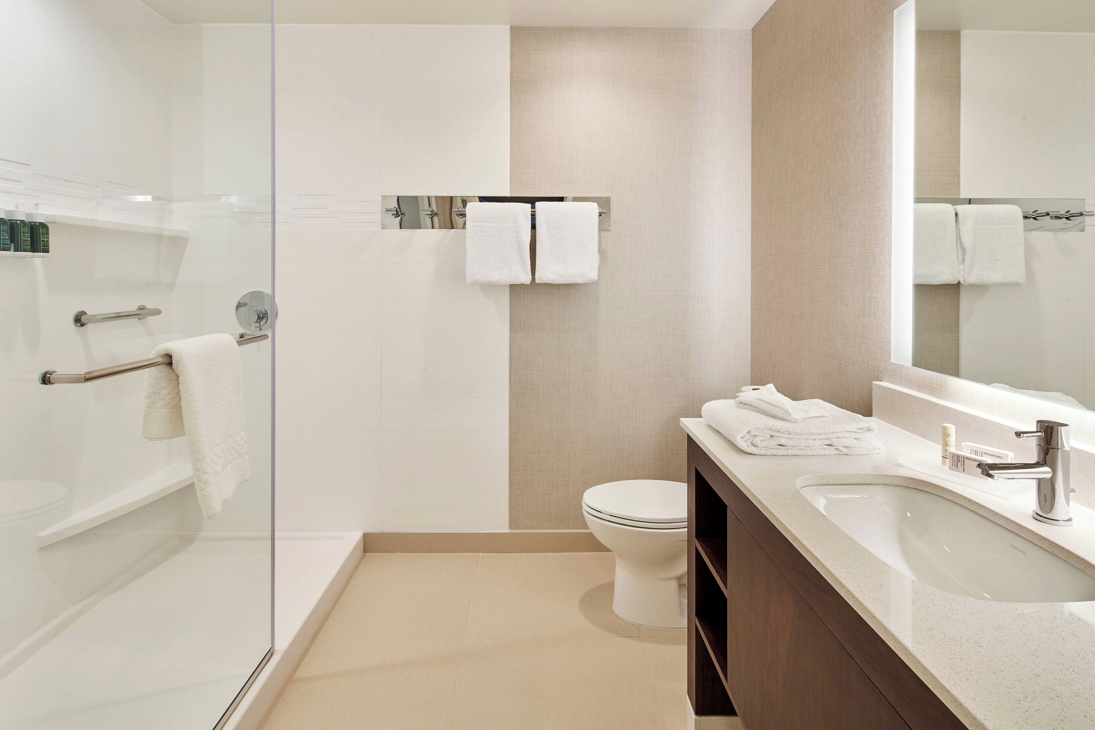 Ein modernes Badezimmer mit Duschkabine aus Glas, Toilette und Waschbecken mit Waschtisch.