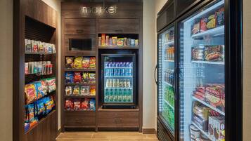 A self-service snack and beverage area with refrigerated sections and shelves stocked with various snacks and drinks.